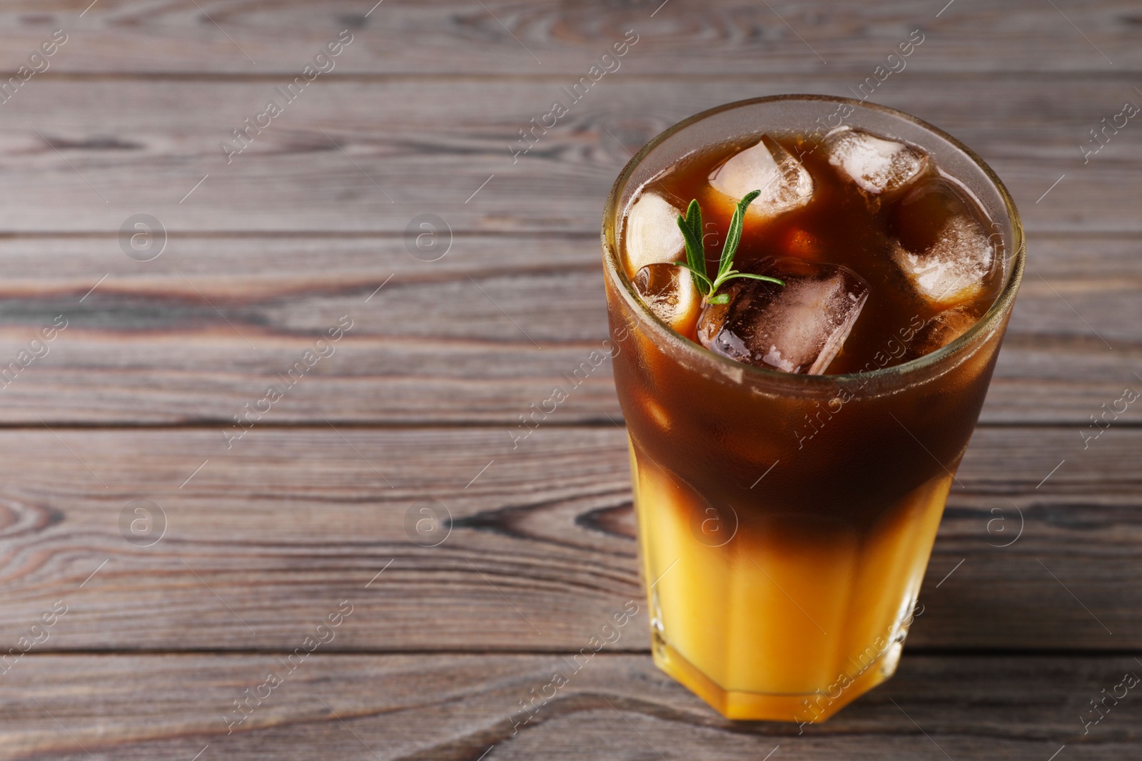 Photo of Tasty refreshing drink with coffee and orange juice on wooden table, space for text