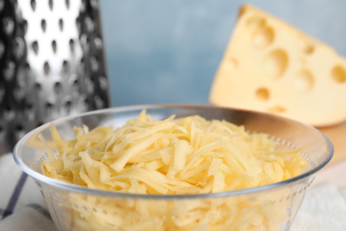 Photo of Delicious grated cheese in glass bowl on table, closeup