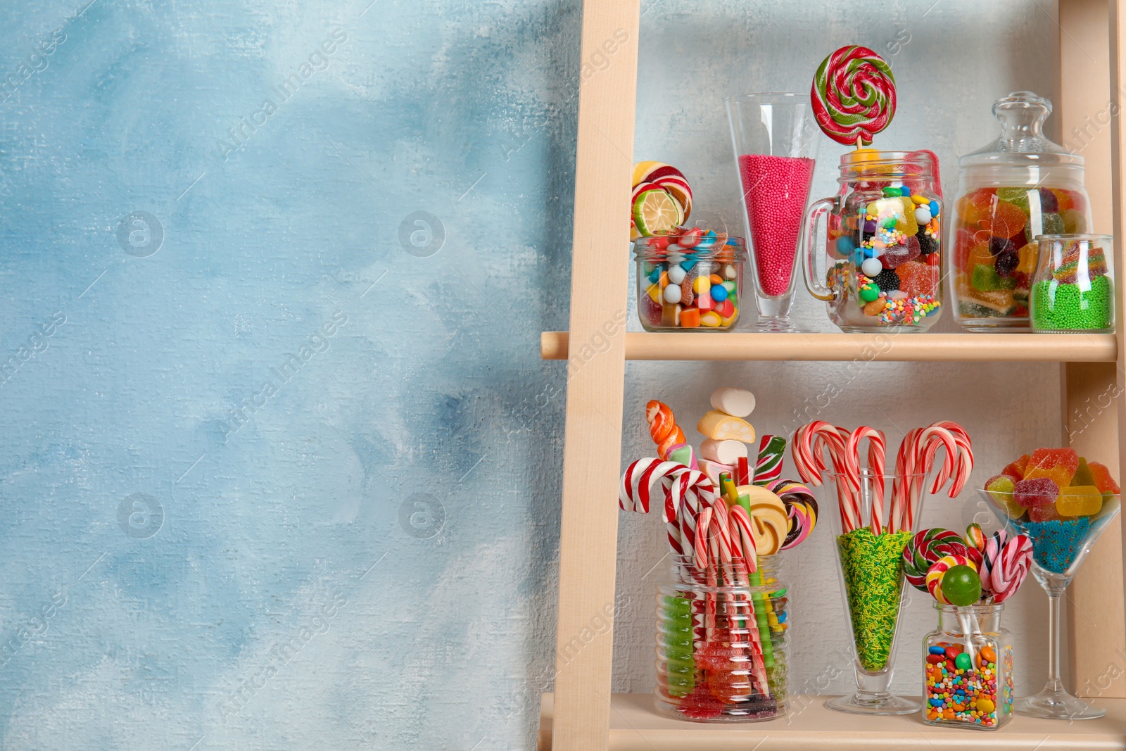 Photo of Many different yummy candies on wooden shelves. Space for text