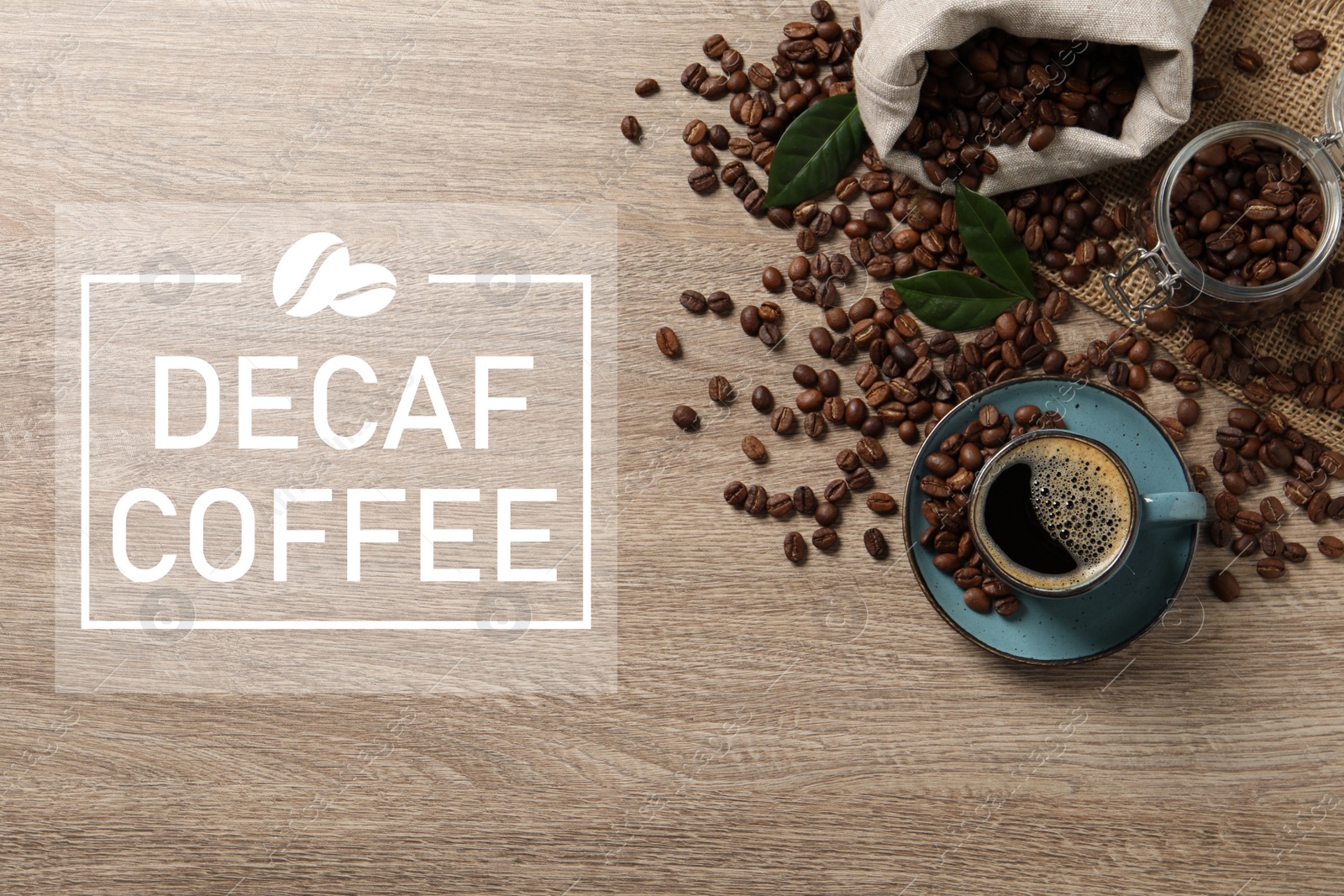 Image of Cup of aromatic decaf coffee and beans on wooden table, flat lay