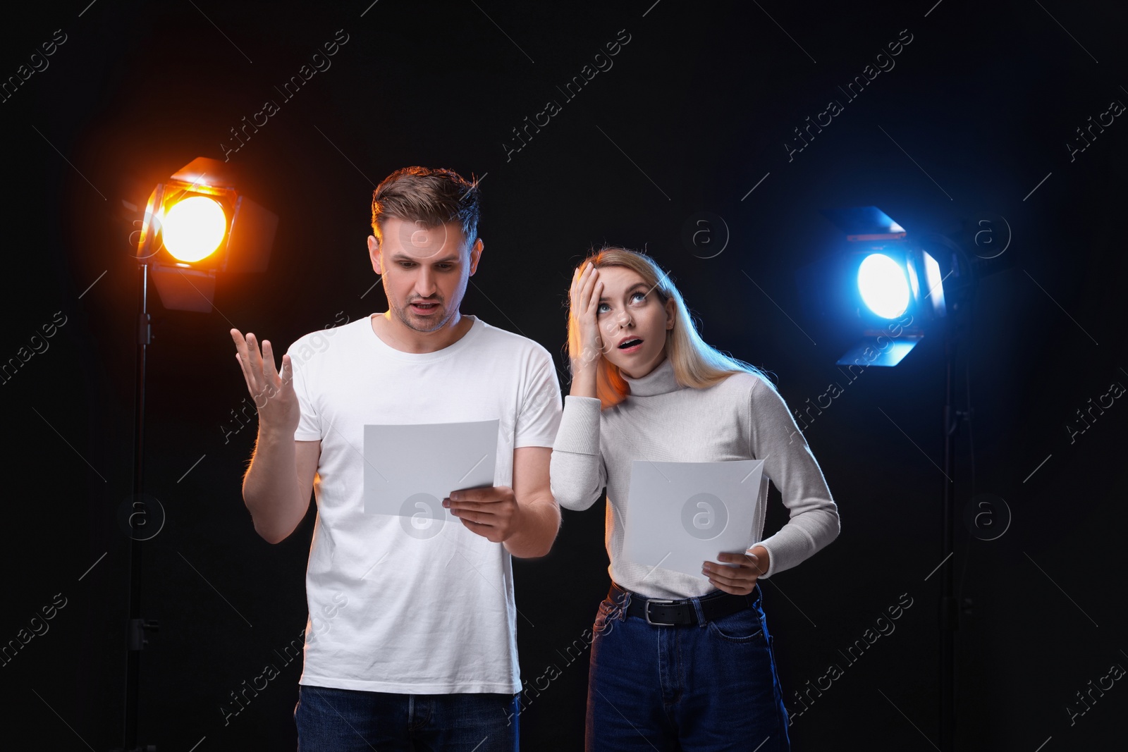 Photo of Casting call. Emotional woman and man with script performing on black background