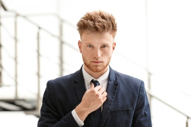 Portrait of handsome young man in elegant suit indoors