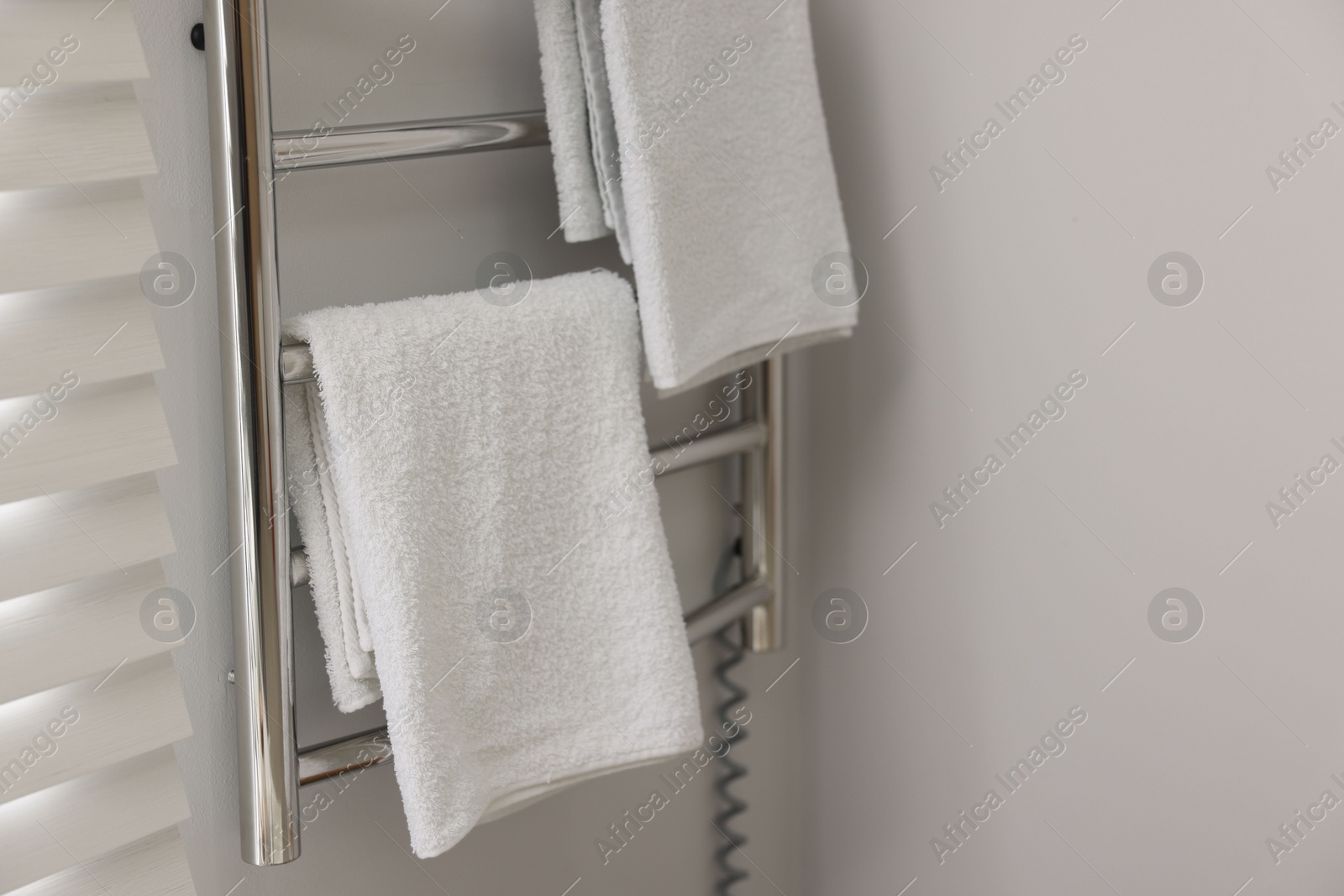 Photo of Heated towel rail with towels in bathroom