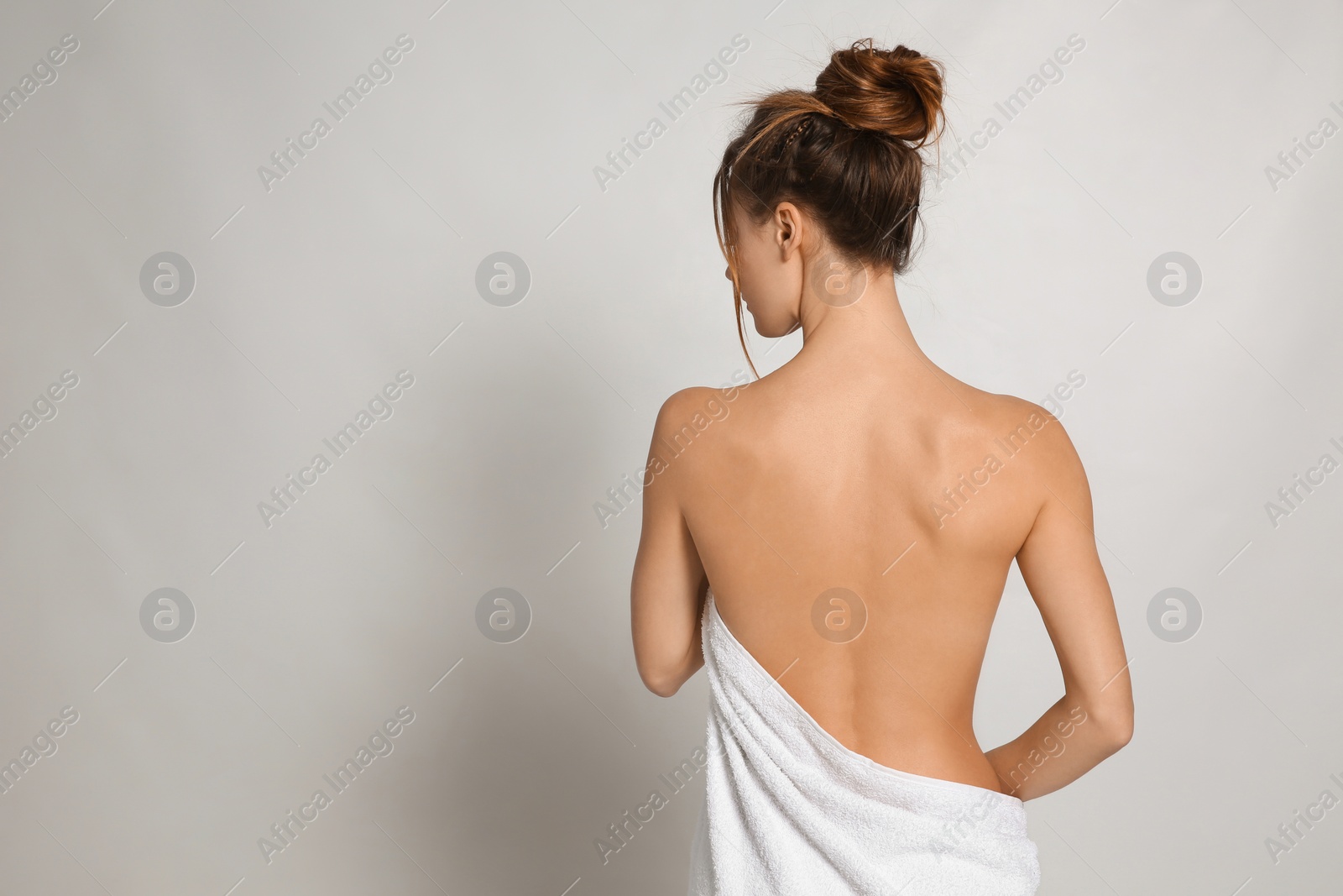 Photo of Back view of woman with perfect smooth skin on light grey background, space for text. Beauty and body care