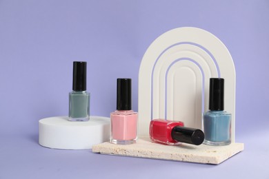Photo of Stylish presentation of nail polishes on lilac background