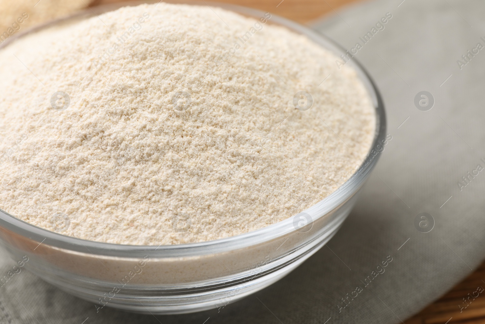 Photo of Glass bowl with quinoa flour on table, closeup