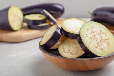 Photo of Wooden bowl with cut eggplant on table