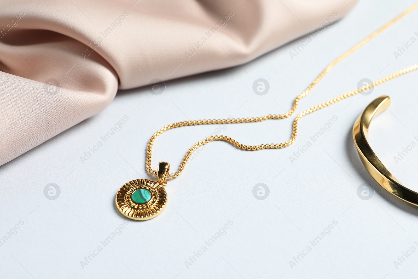 Photo of Elegant necklace and beige cloth on white table, closeup