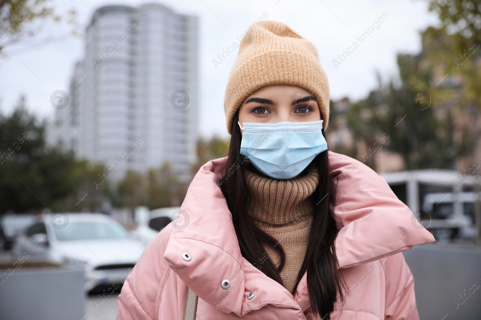 Photo of Young woman in medical face mask walking outdoors. Personal protection during COVID-19 pandemic