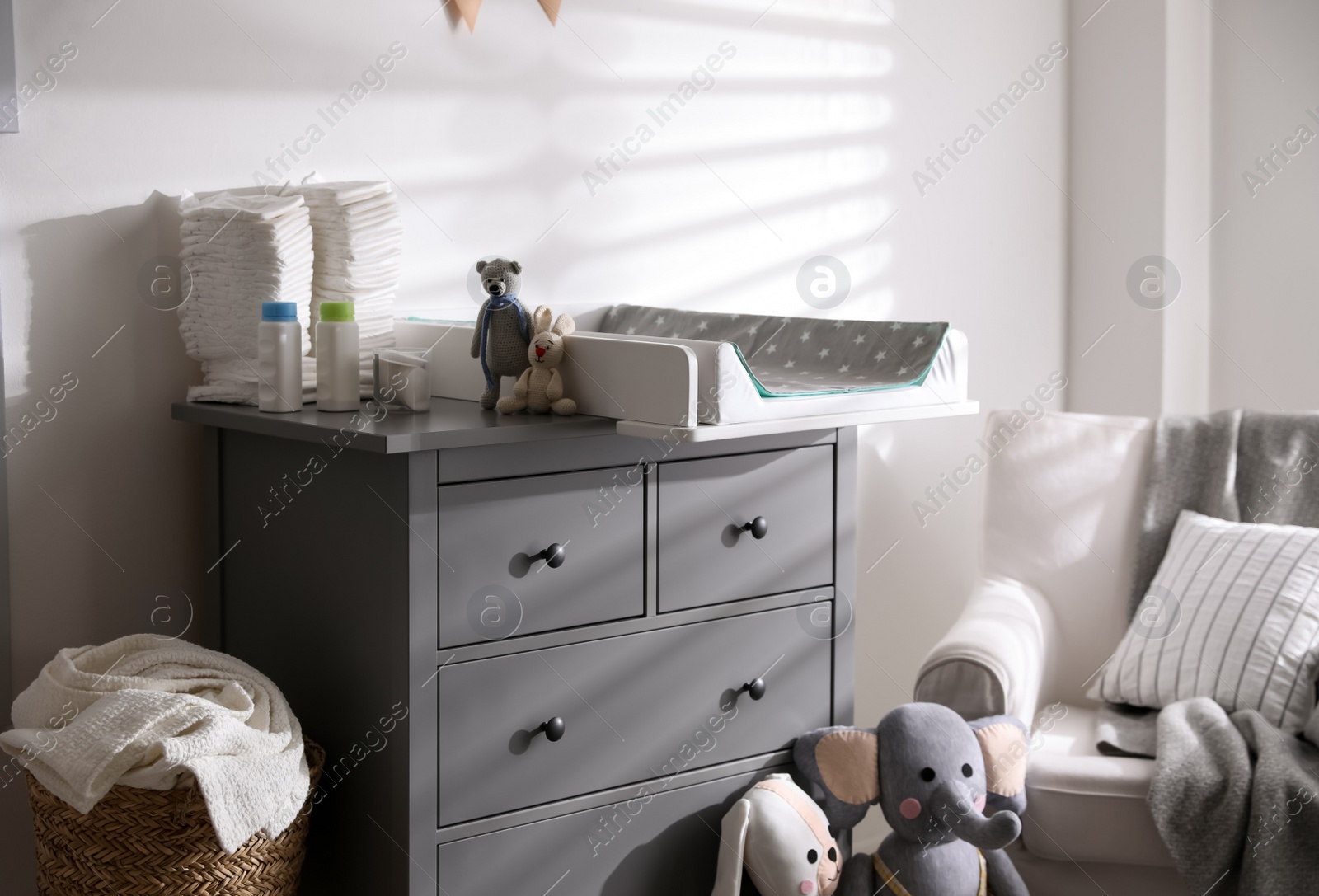 Photo of Chest of drawers with changing tray and pad in baby room. Interior design