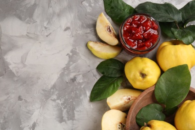 Delicious quince jam and fruits on light grey table, flat lay. Space for text