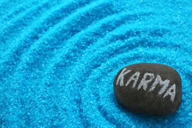 Photo of Stone with word Karma on light blue sea salt. Space for text