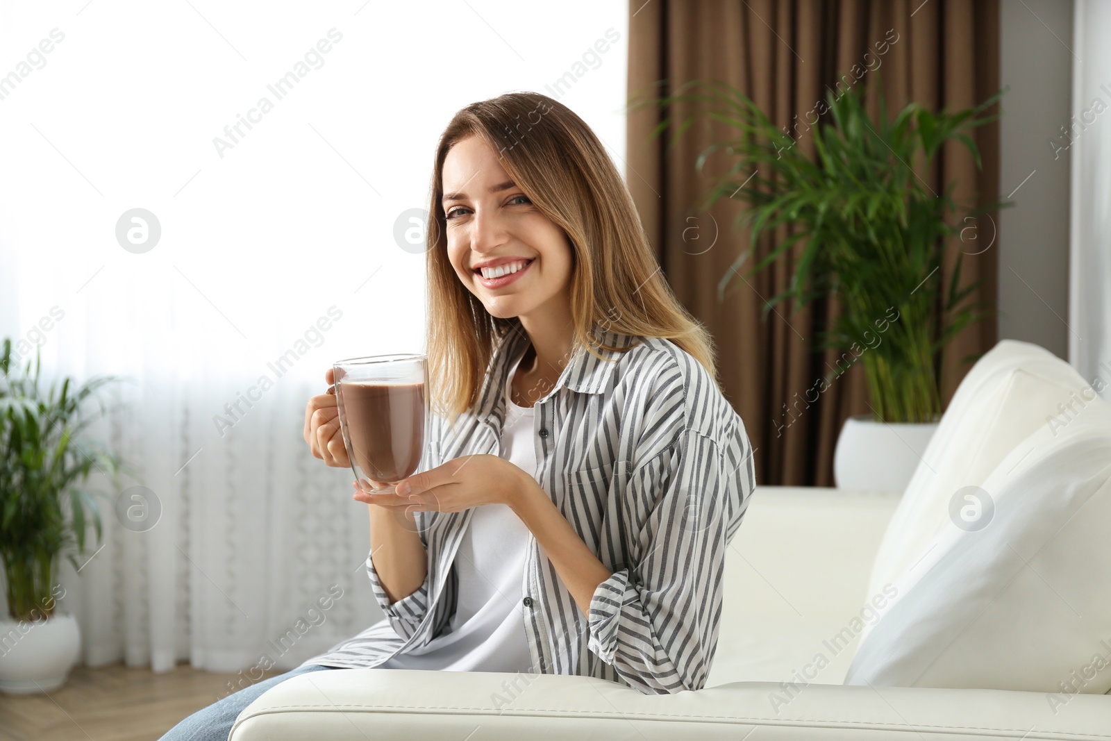 Photo of Young woman with glass cup of chocolate milk in room