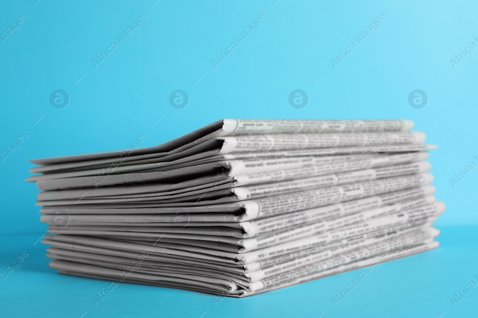 Photo of Stack of newspapers on light blue background. Journalist's work