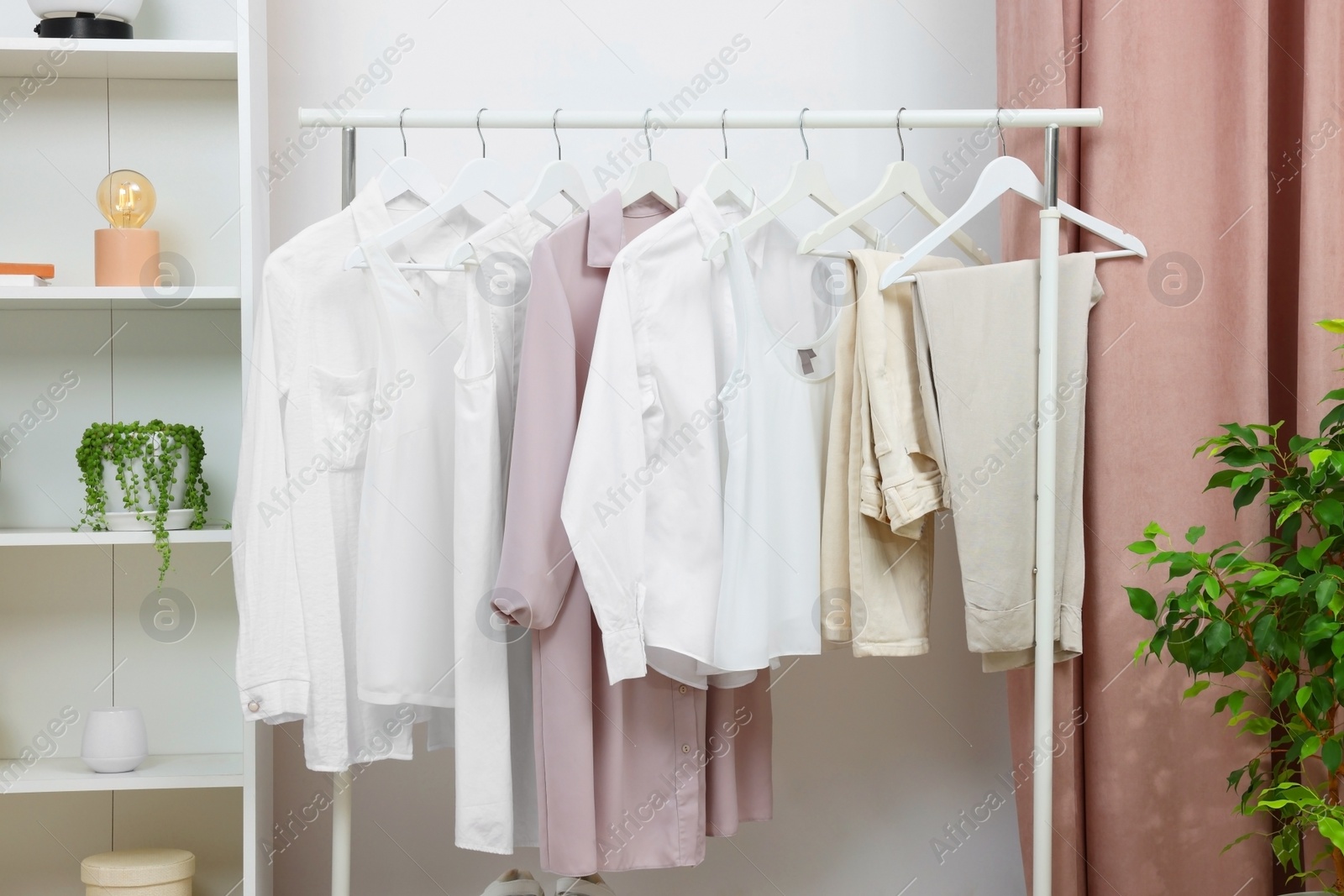 Photo of Rack with different stylish women`s clothes indoors