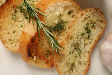 Photo of Tasty baguette with garlic, dill and rosemary on table, flat lay