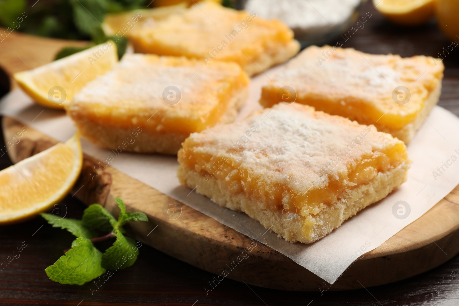 Photo of Tasty lemon bars with powdered sugar and mint on table, closeup