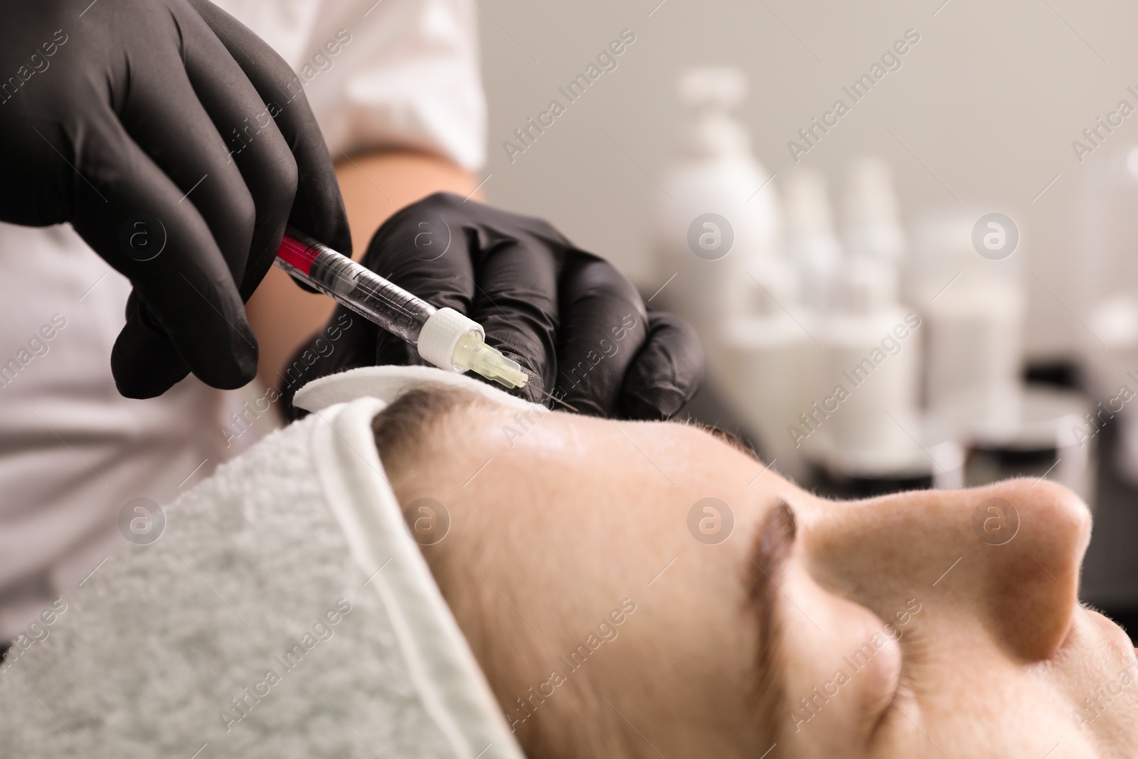 Photo of Cosmetologist giving facial injection to patient in clinic, closeup. Cosmetic surgery