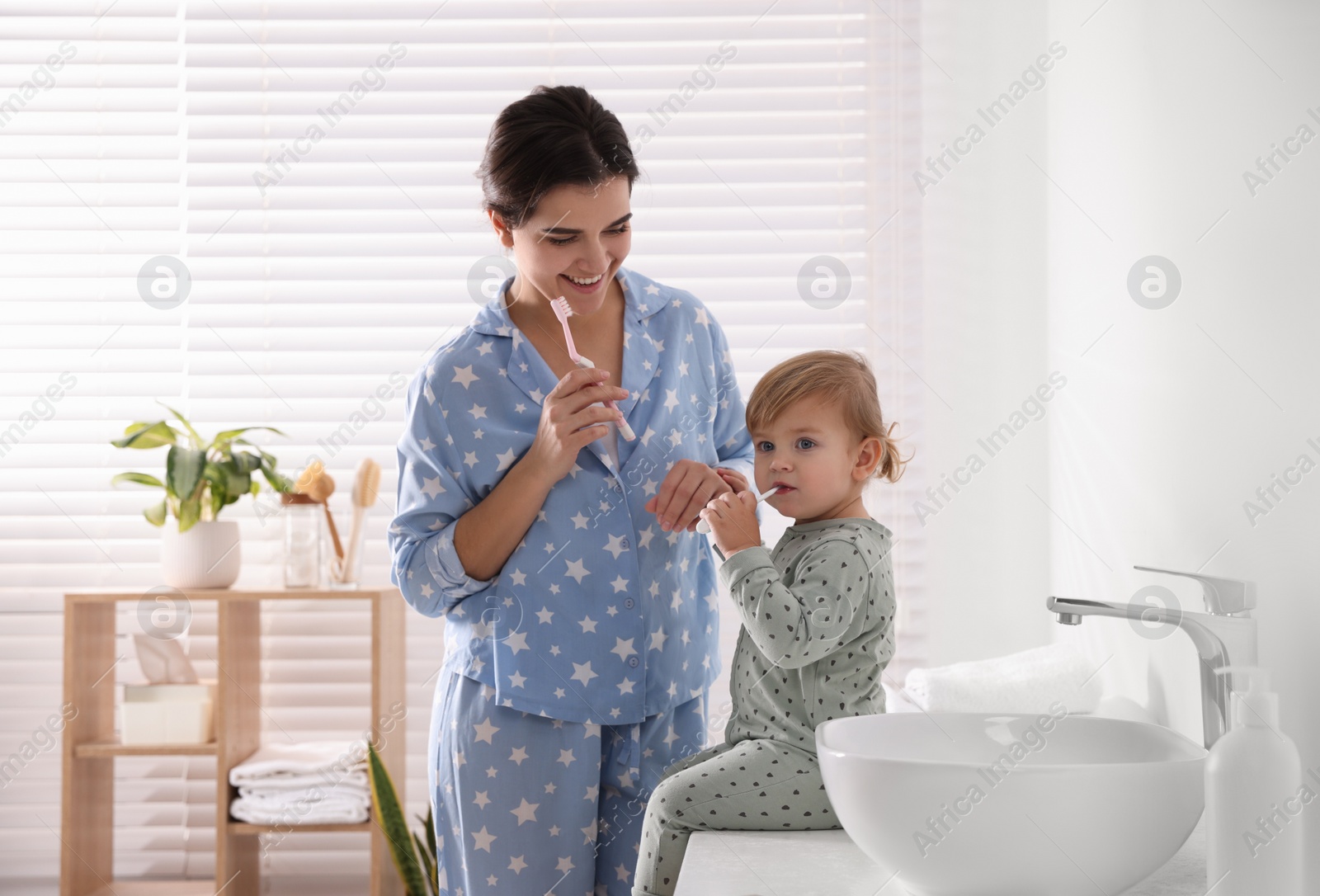 Photo of Mother and her daughter brushing teeth together in bathroom