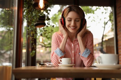 Young woman with headphones listening to music in cafe