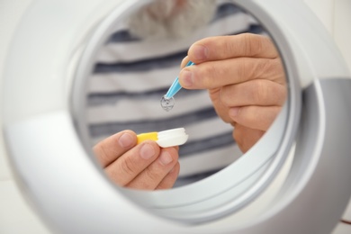 Mirror reflection of senior man taking contact lens from container