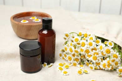 Photo of Composition with chamomile flowers and cosmetic products on table