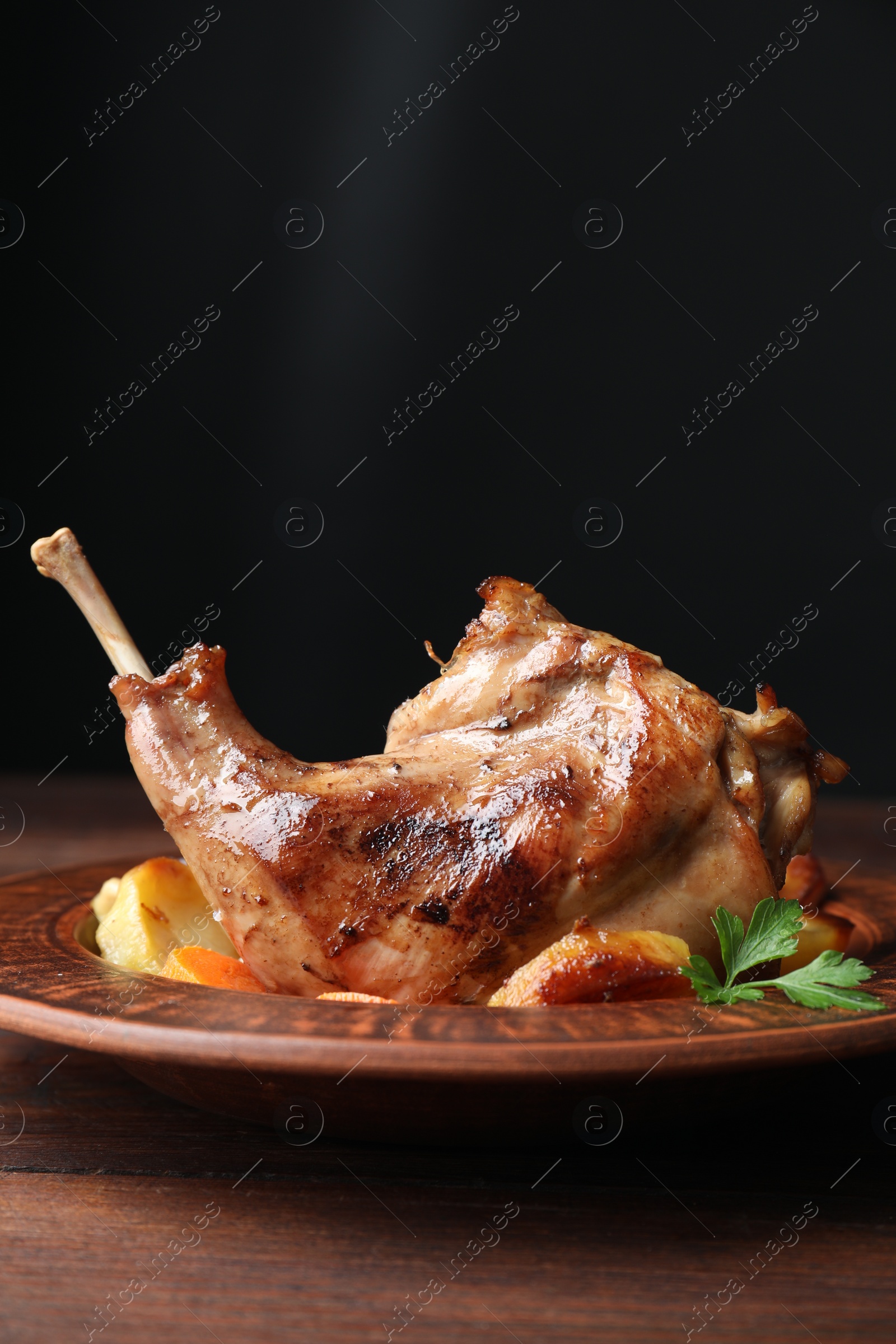 Photo of Tasty cooked rabbit meat with potatoes on wooden table