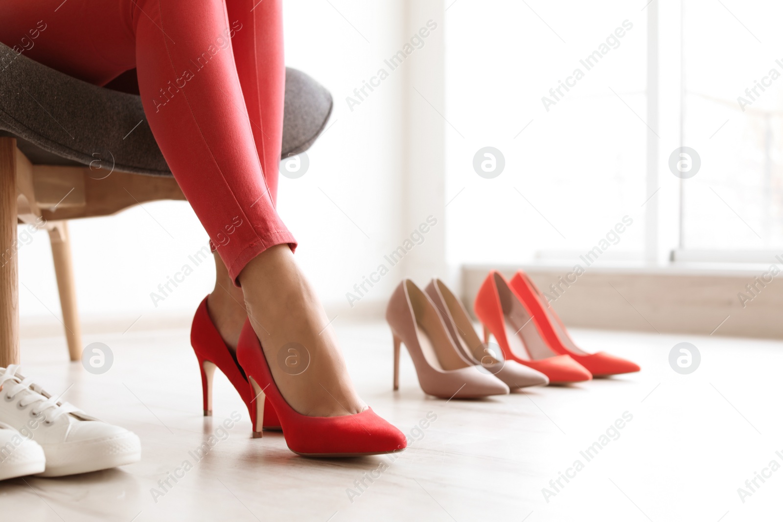 Photo of Young woman choosing shoes while sitting in armchair