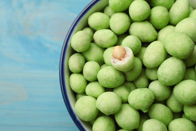 Tasty wasabi coated peanuts in bowl on turquoise table, top view