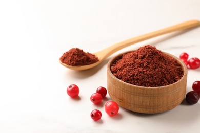 Photo of Dried cranberry powder and fresh berries on white table, closeup. Space for text