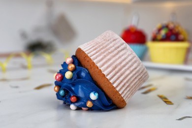 Photo of Cupcake dropped on white table, closeup. Troubles happen