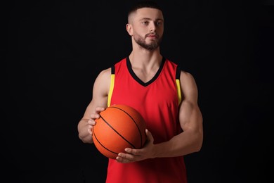 Photo of Athletic young man with basketball ball on black background