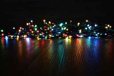 Photo of Beautiful colorful Christmas lights on wooden table. Space for text