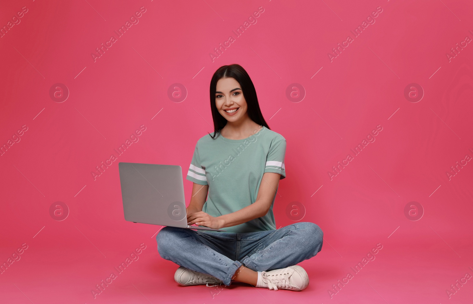 Photo of Young woman with modern laptop on pink background. Space for text