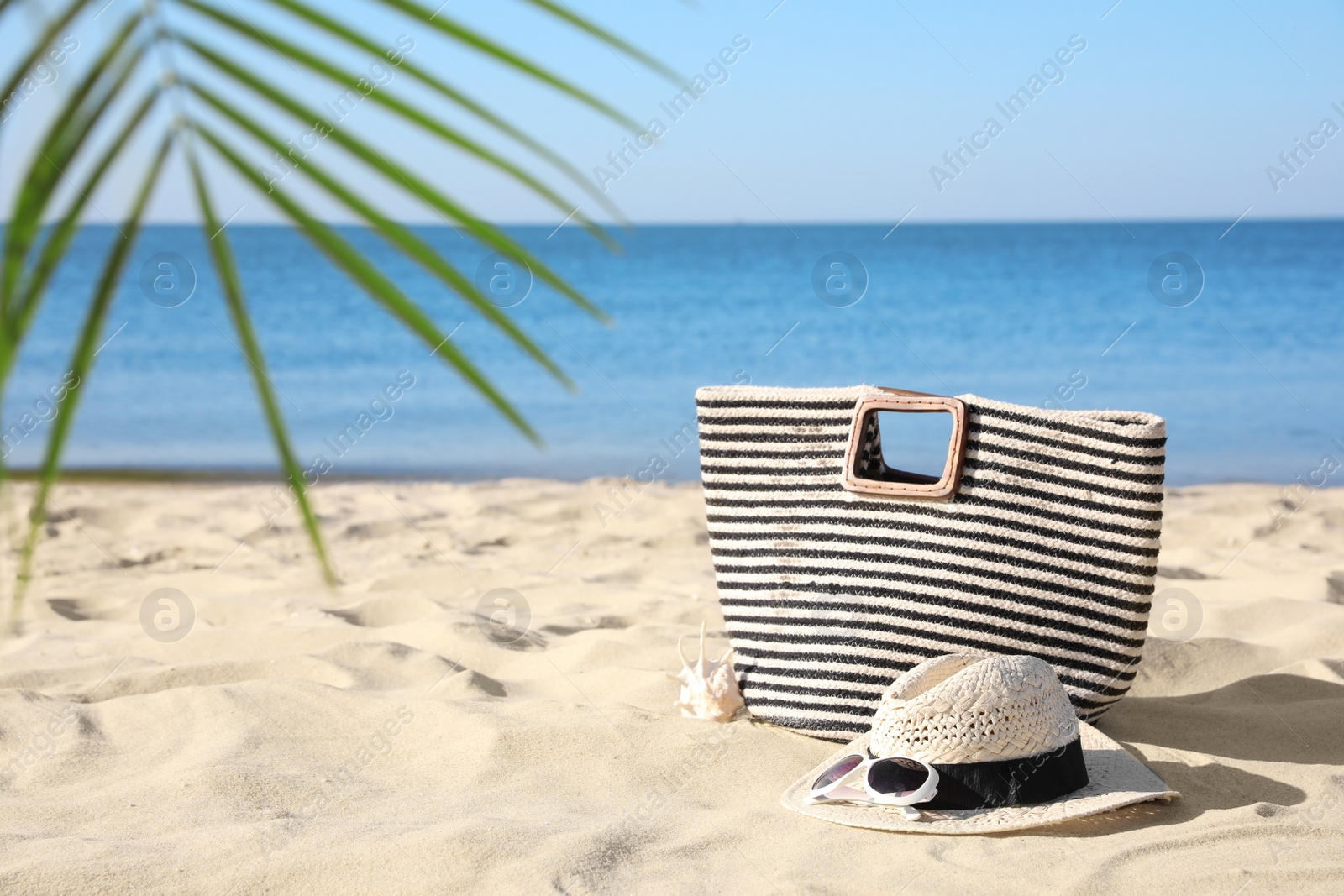 Photo of Stylish beach accessories on sand near sea