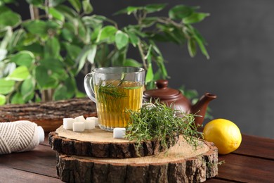 Aromatic herbal tea, fresh tarragon sprigs and sugar cubes on wooden table