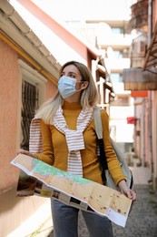 Tourist in protective mask with map on city street