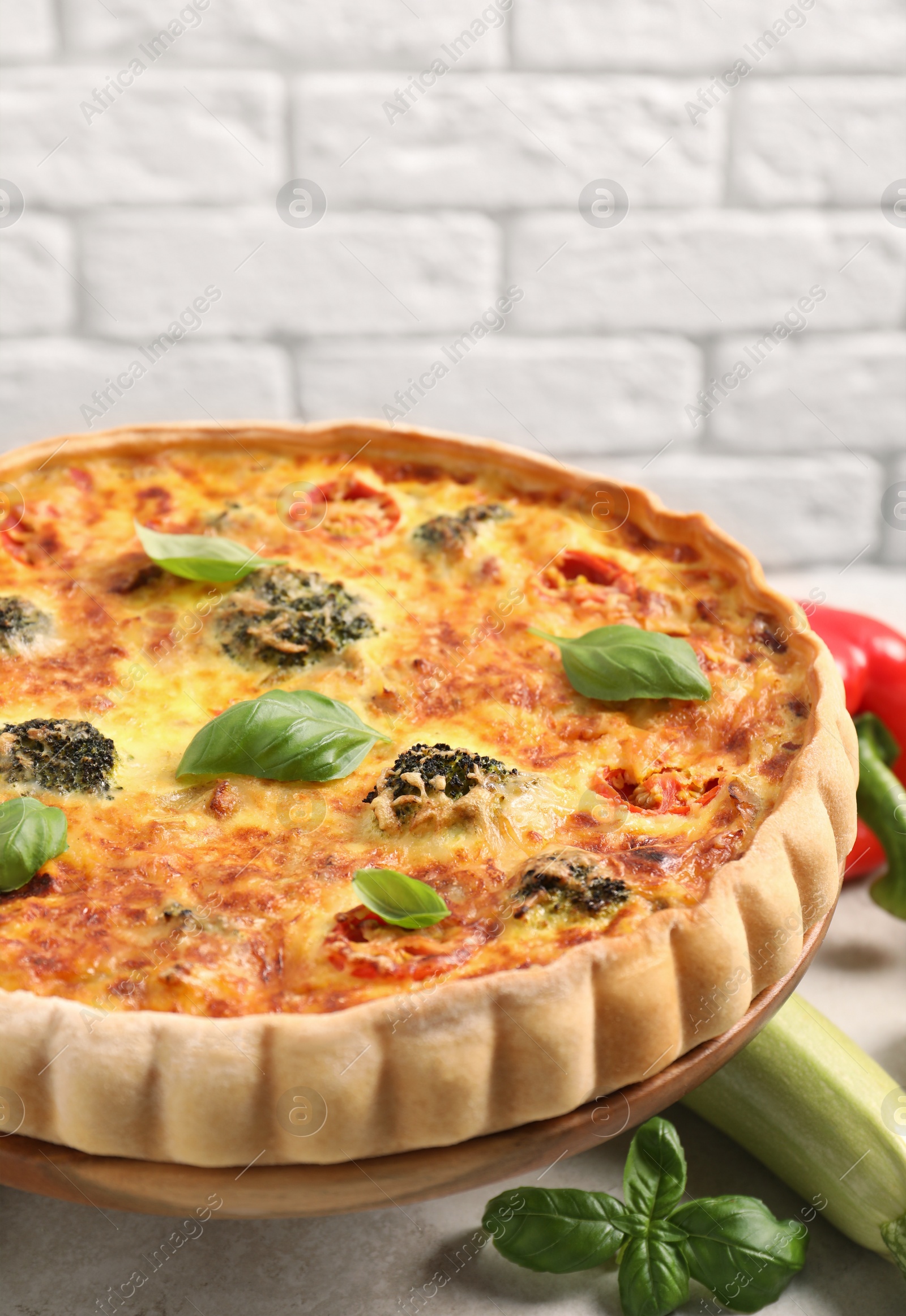 Photo of Delicious homemade vegetable quiche and ingredients on table