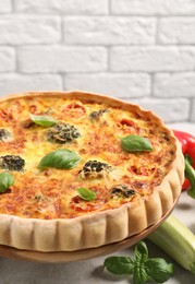 Delicious homemade vegetable quiche and ingredients on table