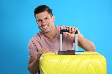 Photo of Happy man with suitcase for summer trip on blue background. Vacation travel