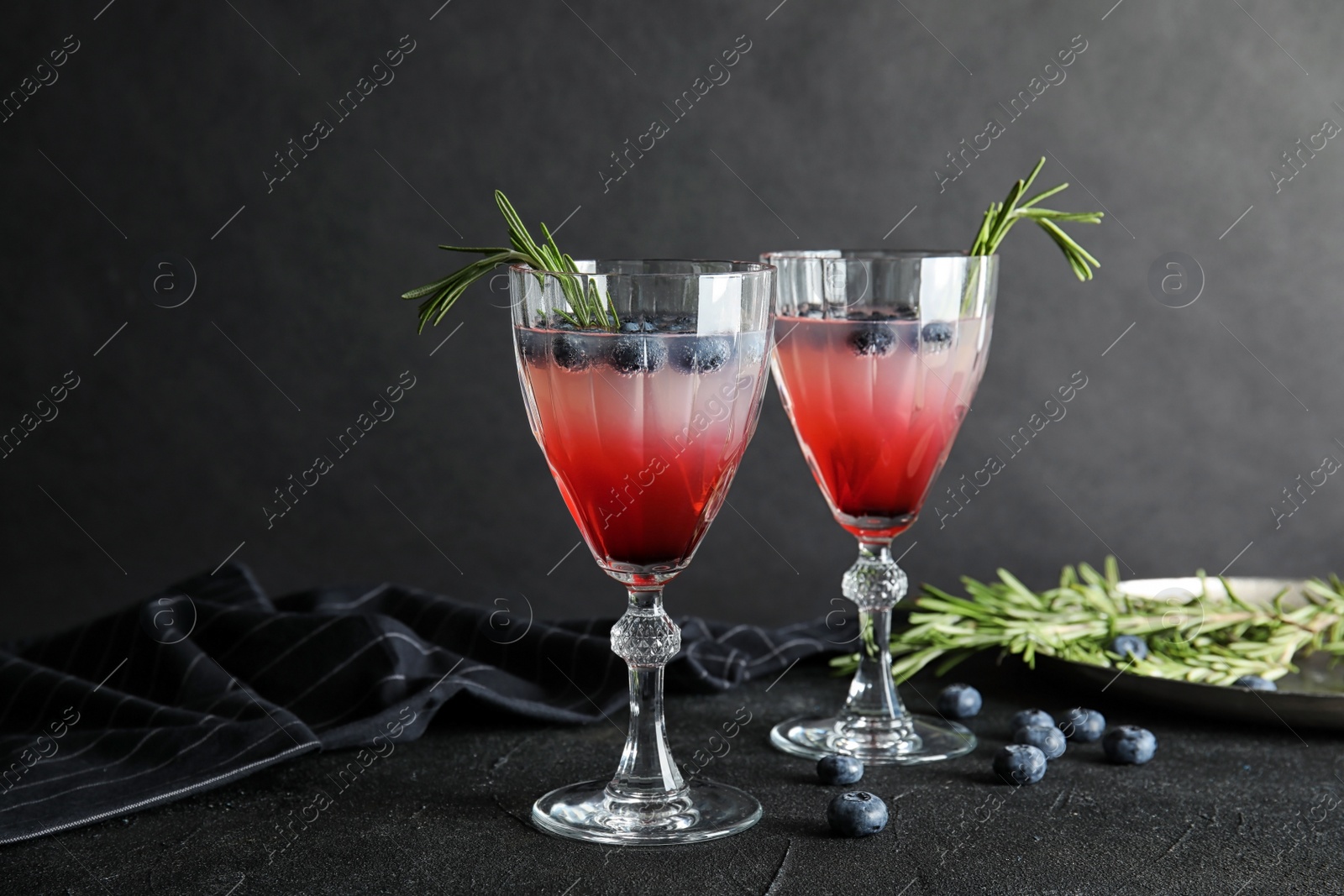 Photo of Glasses of refreshing blueberry cocktail with rosemary on table
