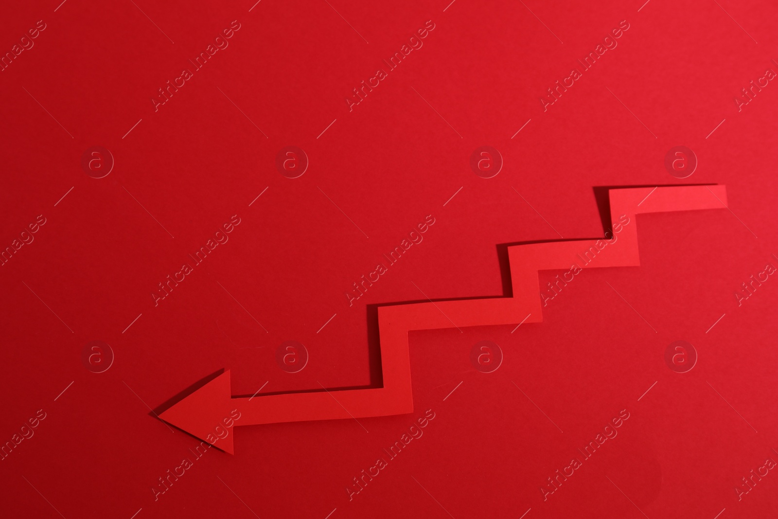 Photo of One zigzag paper arrow on red background, top view. Space for text