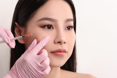 Woman getting facial injection on white background, closeup