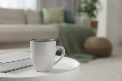 Photo of Ceramic mug and book on white table indoors. Mockup for design