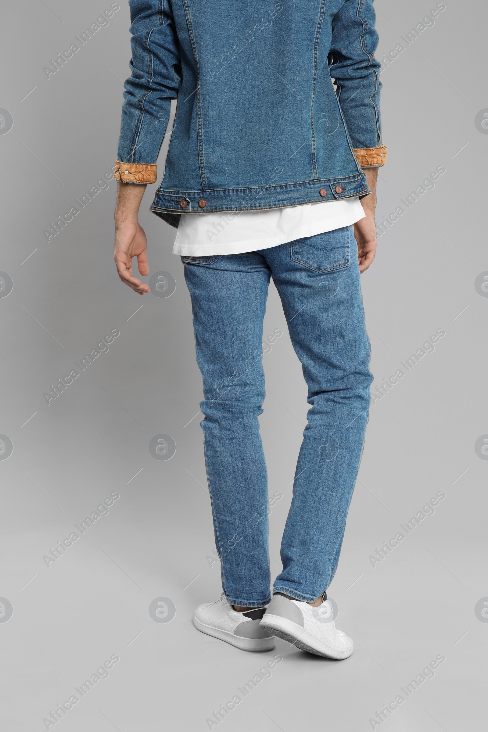 Photo of Young man in stylish jeans on grey background, closeup