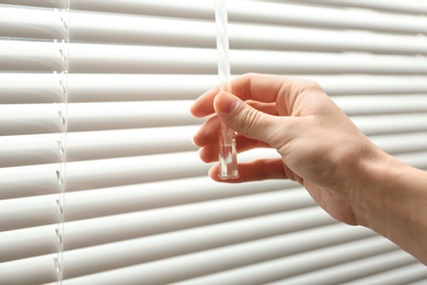 Photo of Woman opening window blinds, closeup. Space for text