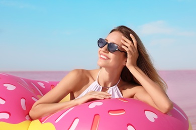 Beautiful woman with inflatable ring near pink lake