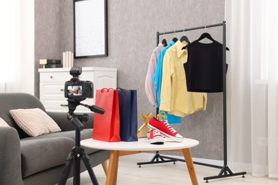 Photo of Fashion blogger's workplace. Sneakers, shopping bags, camera and clothes indoors