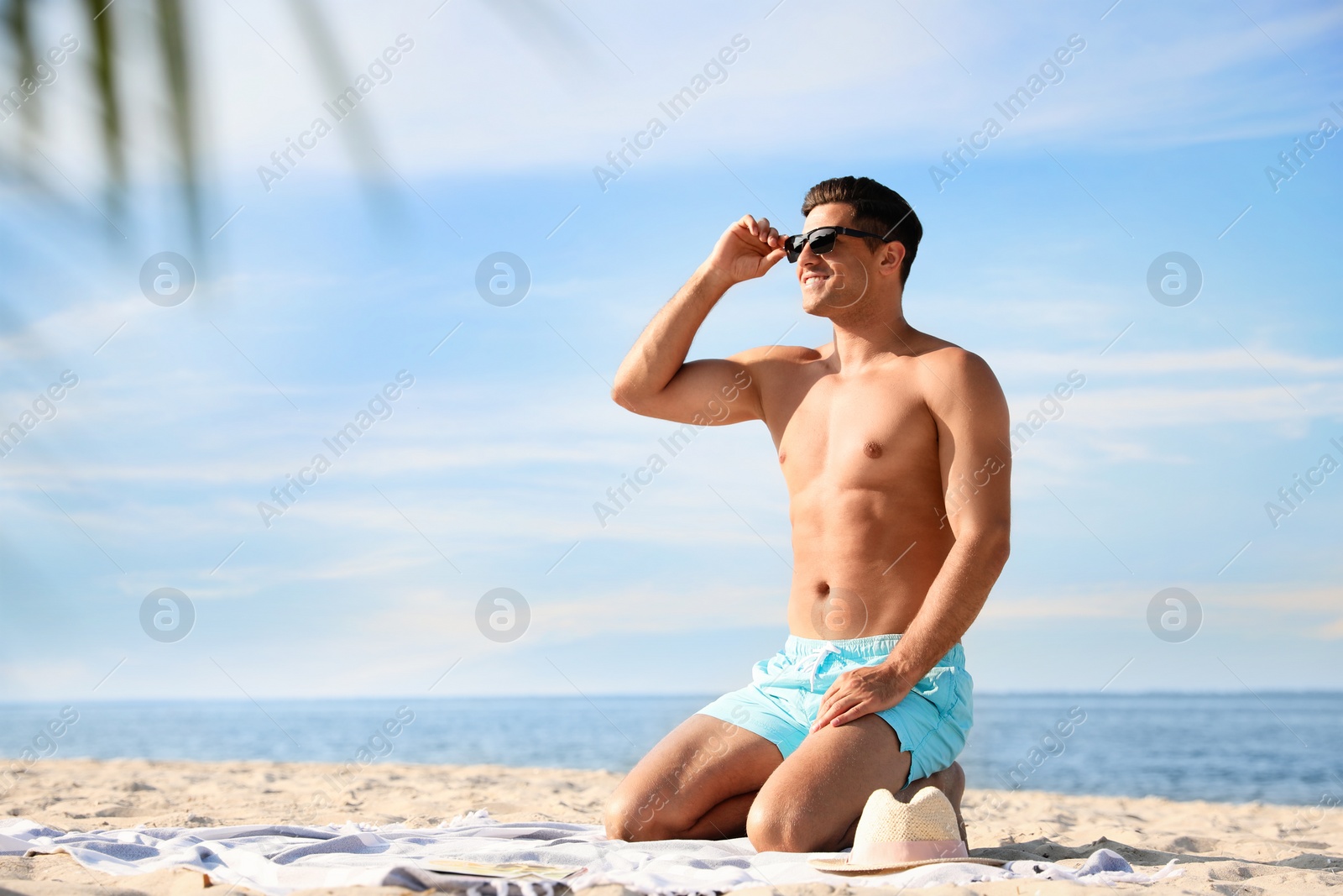 Photo of Happy man with slim body resting on beach. Space for text