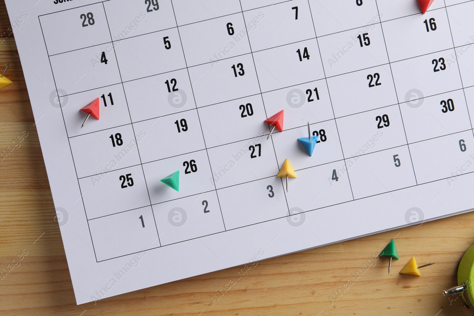 Photo of Timetable. Calendar page and drawing pins on wooden table, top view